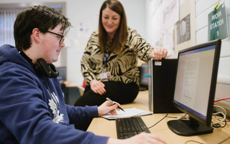 Student and tutor beside computer monitor