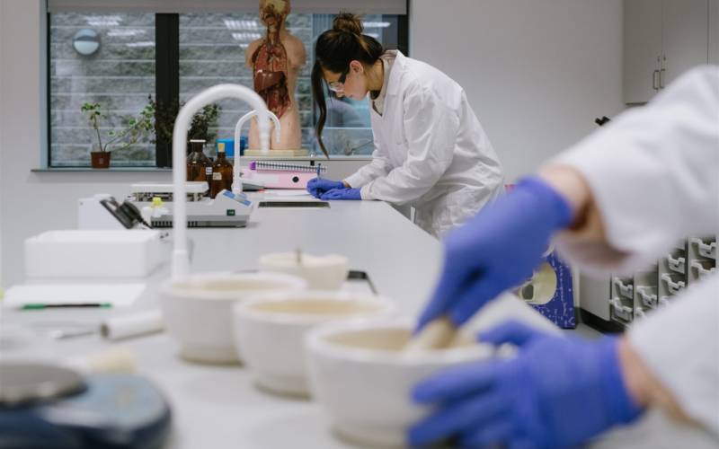 South West College science lab, students are wearing white lab coats and science equipment such as microscopes