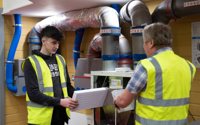 South West College construction and trades student with lecturer in workshop wearing high-vis jackets