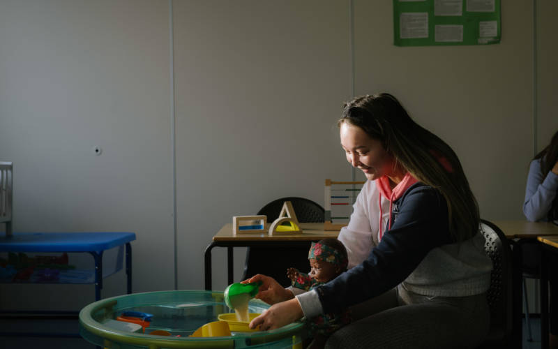 Student sitting in childcare setting at sand tray