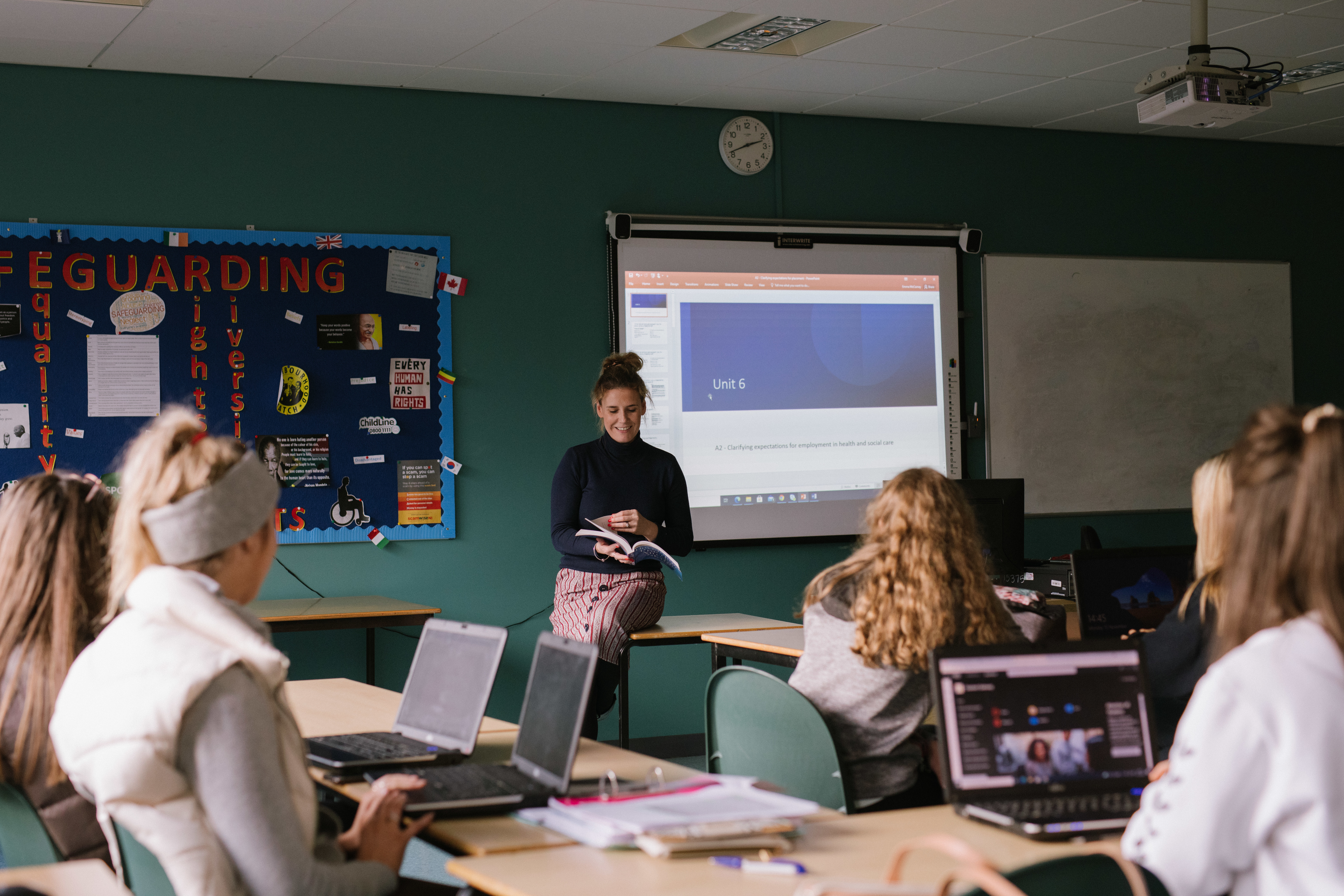 SWC students and teacher in classroom. Students are seated at desks and using laptops.
