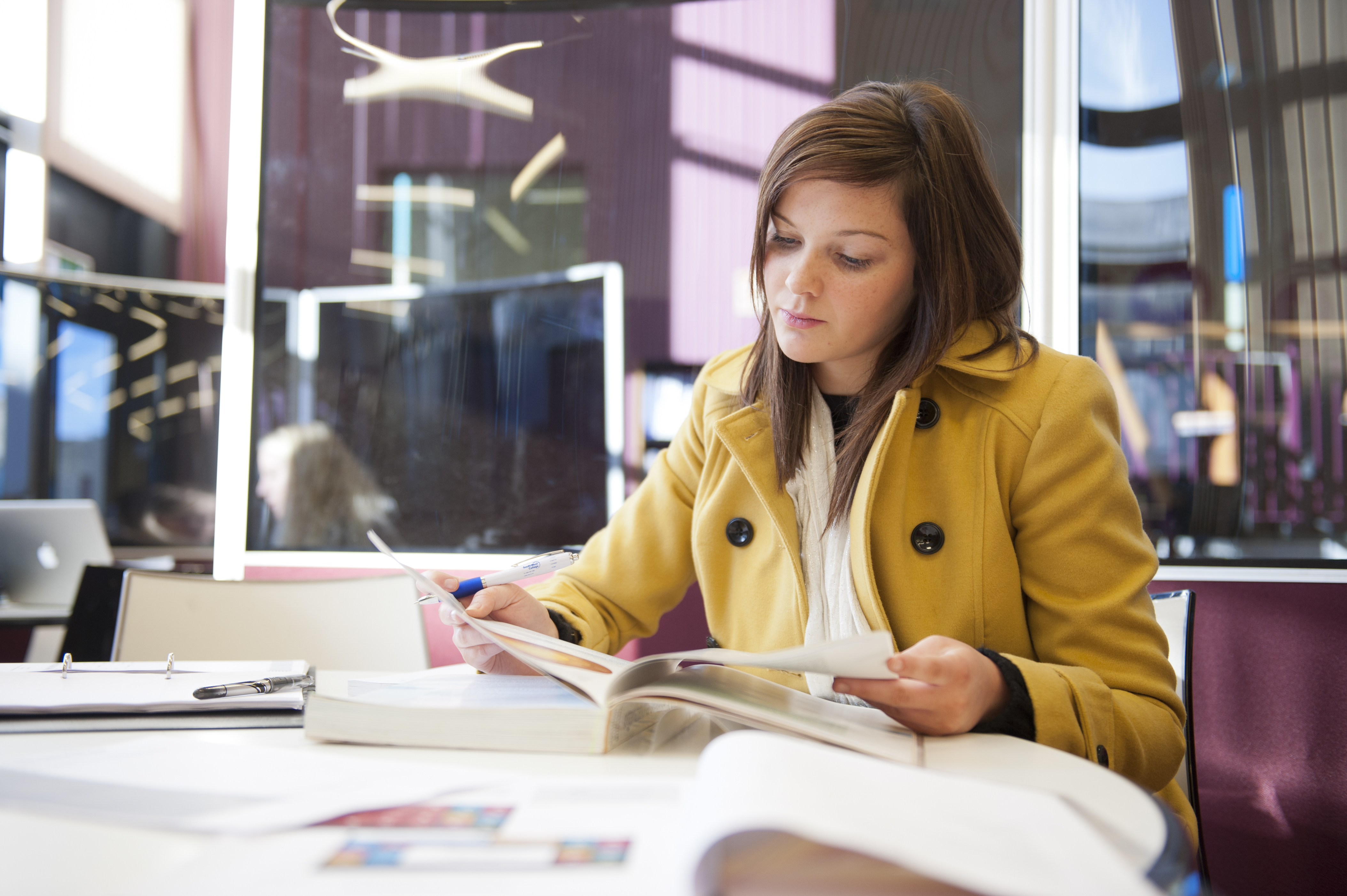Student reading textbook in South West College library