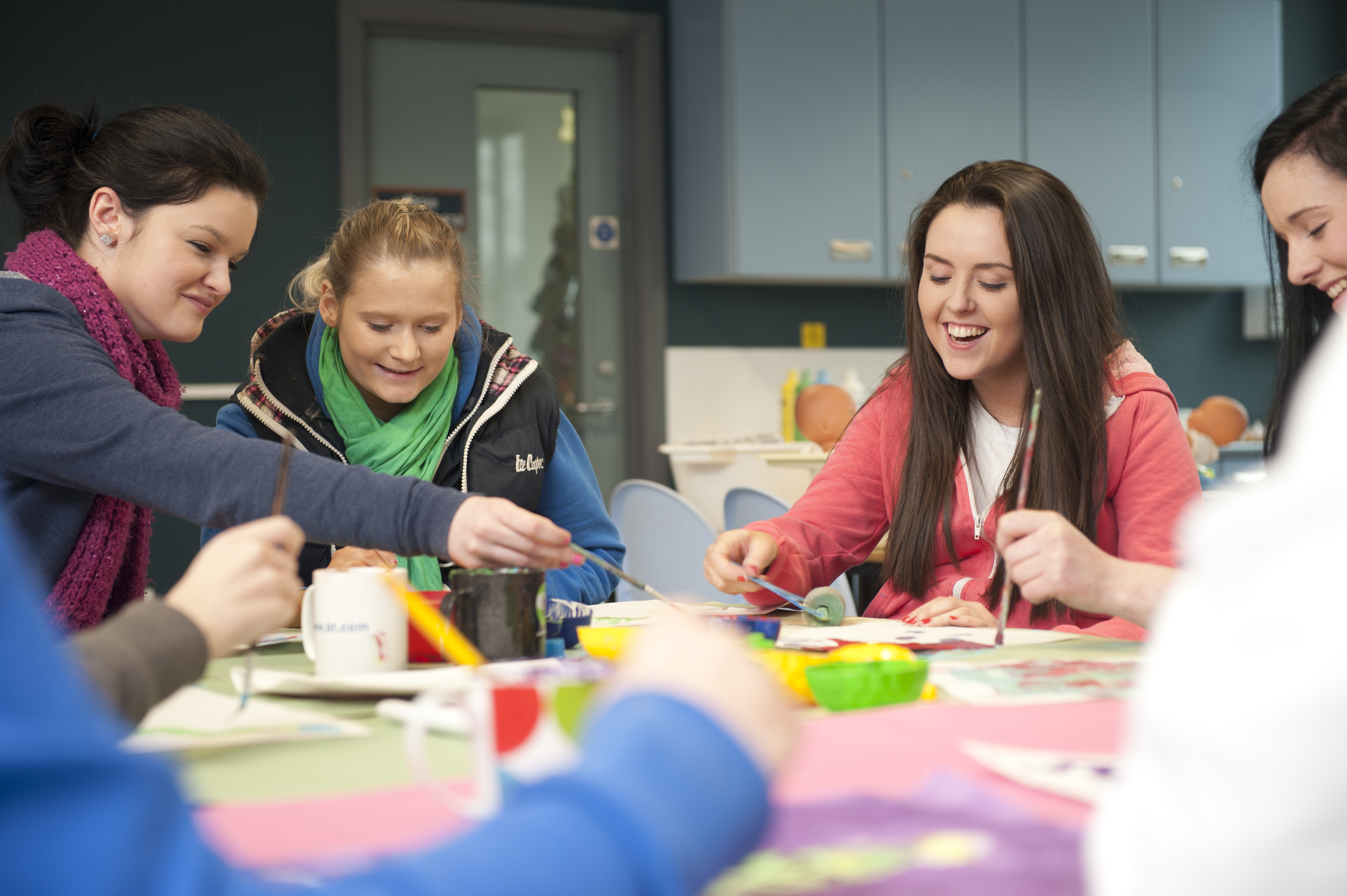 Students are working around a table, they are smiling and laughing