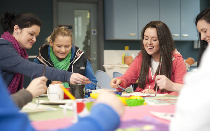 Students are working around a table, they are smiling and laughing