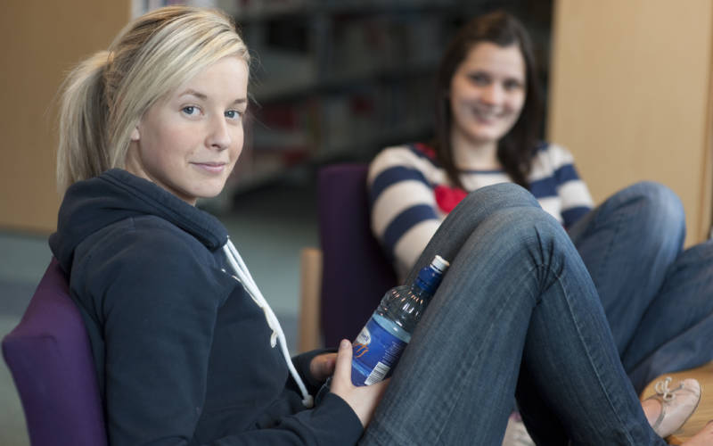 Two smiling students relaxing in one of the SWC campuses