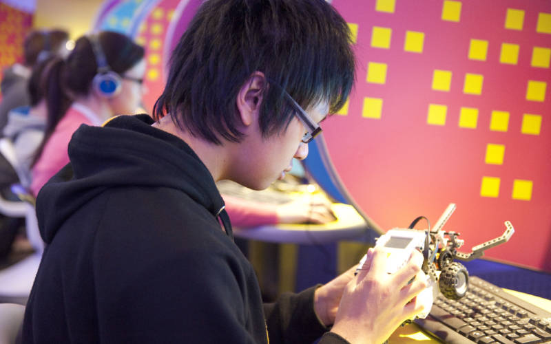 Student in IT lab programming a small robot device